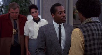 Movie still from “Brewster's Millions” (1985), directed by Walter Hill – A group of people standing in a room; Medium shot, Over the shoulder angle