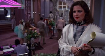 Movie still from “Brewster's Millions” (1985), directed by Walter Hill – A woman standing in front of a group of people; Medium shot, Over the shoulder angle