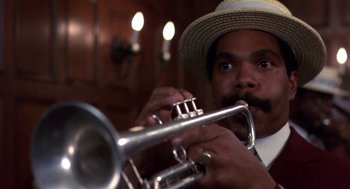 Movie still from “Brewster's Millions” (1985), directed by Walter Hill – A man in a straw hat playing a trumpet; Close Up shot, Low angle