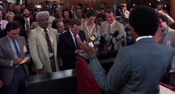 Movie still from “Brewster's Millions” (1985), directed by Walter Hill – A crowd of people standing around a microphone; Medium shot, High angle