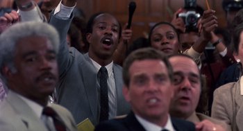 Movie still from “Brewster's Millions” (1985), directed by Walter Hill – A group of people standing in a room with microphones; Close Up shot, High angle