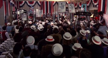 Movie still from “Brewster's Millions” (1985), directed by Walter Hill – A crowd of people wearing white hats and holding signs; Wide shot, High angle