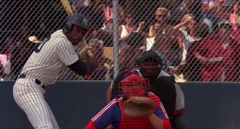 Movie still from “Brewster's Millions” (1985), directed by Walter Hill – A baseball player holding a catchers mitt in front of a crowd of people; Medium shot, Over the shoulder angle