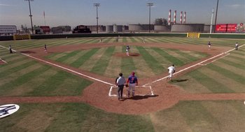 Movie still from “Brewster's Millions” (1985), directed by Walter Hill – A group of men standing on top of a baseball field; Extreme Wide shot, High angle