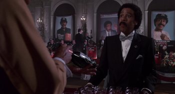 Movie still from “Brewster's Millions” (1985), directed by Walter Hill – A man in a suit and a bow tie is holding a wine glass; Medium shot, Low angle