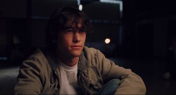 Movie still from “Brick” (2005), directed by Rian Johnson – A young man sitting in a chair in a dark room; Close Up shot, High angle