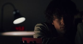 Movie still from “Brick” (2005), directed by Rian Johnson – A young man sitting in front of a laptop computer in a dark room; Close Up shot, Low angle