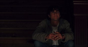 Movie still from “Brick” (2005), directed by Rian Johnson – A man sitting on the steps holding a wine glass; Medium shot, Low angle