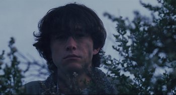 Movie still from “Brick” (2005), directed by Rian Johnson – A young man with long dark hair looking at the camera; Close Up shot, Low angle