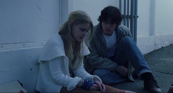 Movie still from “Brick” (2005), directed by Rian Johnson – A young man and a young woman sitting next to each other on the ground; Medium shot, Low angle