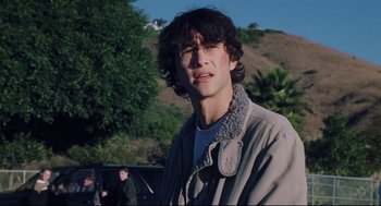 Movie still from “Brick” (2005), directed by Rian Johnson – A young man wearing a jacket and headphones in a parking lot; Close Up shot, Over the shoulder angle