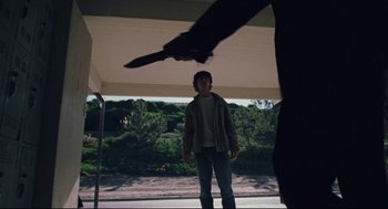 Movie still from “Brick” (2005), directed by Rian Johnson – A man holding a knife in front of another man; Wide shot, Low angle