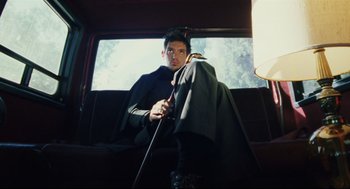 Movie still from “Brick” (2005), directed by Rian Johnson – A man sitting in a car holding a sword; Medium shot, Low angle