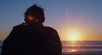 Movie still from “Brick” (2005), directed by Rian Johnson – A person is looking out at the sun setting over the ocean; Medium shot, Over the shoulder angle