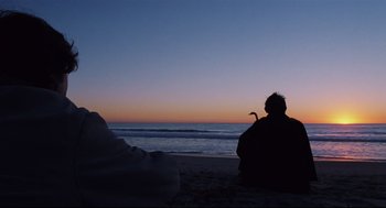 Movie still from “Brick” (2005), directed by Rian Johnson – A man sitting on the beach watching the sun go down over the ocean; Wide shot, Low angle