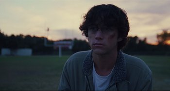 Movie still from “Brick” (2005), directed by Rian Johnson – A young man wearing glasses looking at the camera; Close Up shot, Over the shoulder angle
