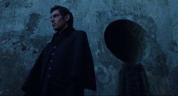 Movie still from “Brick” (2005), directed by Rian Johnson – A man standing in front of a stone wall; Medium shot, Low angle