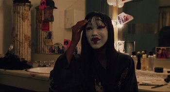 Movie still from “Brick” (2005), directed by Rian Johnson – A woman with a mask is putting makeup on her face; Close Up shot, Over the shoulder angle