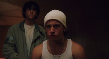Movie still from “Brick” (2005), directed by Rian Johnson – A man with a white hat is looking at the camera with another man standing behind him; Close Up shot, Low angle