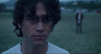 Movie still from “Brick” (2005), directed by Rian Johnson – A young man wearing glasses looking at the camera; Close Up shot, Over the shoulder angle