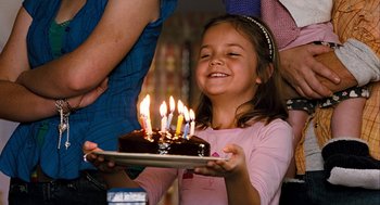 Movie still from “Bridge to Terabithia” (2007), directed by Gabor Csupo – A little girl is holding a cake with candles on it; Close Up shot, Over the shoulder angle