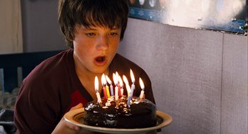 Movie still from “Bridge to Terabithia” (2007), directed by Gabor Csupo – A young boy blowing out candles on a chocolate cake; Close Up shot, High angle