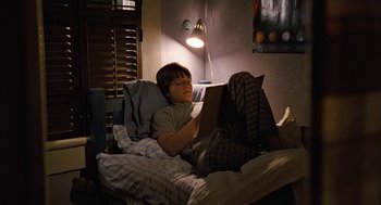 Movie still from “Bridge to Terabithia” (2007), directed by Gabor Csupo – A boy is reading a book in his bed at night; Wide shot, High angle