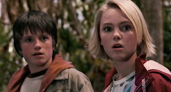Movie still from “Bridge to Terabithia” (2007), directed by Gabor Csupo – A boy and a girl standing next to each other in front of trees; Close Up shot, Low angle