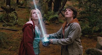 Movie still from “Bridge to Terabithia” (2007), directed by Gabor Csupo – Two young people are holding a light in the woods; Medium shot, Low angle