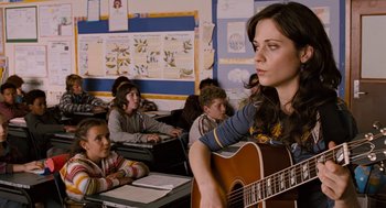 Movie still from “Bridge to Terabithia” (2007), directed by Gabor Csupo – A woman holding a guitar in front of a group of children; Medium shot, Over the shoulder angle