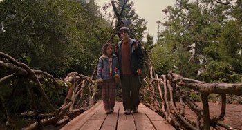 Movie still from “Bridge to Terabithia” (2007), directed by Gabor Csupo – A man and a girl are standing on a wooden bridge; Wide shot, High angle