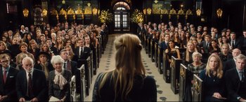 Movie still from “Bridget Jones's Baby” (2016), directed by Sharon Maguire – A crowd of people sitting in rows in front of a woman; Wide shot, High angle