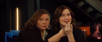 Movie still from “Bridget Jones's Baby” (2016), directed by Sharon Maguire – Two women sitting next to each other while one of the women has a makeup brush in her mouth; Close Up shot, Over the shoulder angle