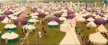 Movie still from “Bridget Jones's Baby” (2016), directed by Sharon Maguire – A group of people standing around tents in a field; Extreme Wide shot, High angle