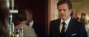 Movie still from “Bridget Jones's Baby” (2016), directed by Sharon Maguire – A man in a suit and tie standing next to another man in a suit and tie; Close Up shot, Over the shoulder angle