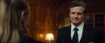 Movie still from “Bridget Jones's Baby” (2016), directed by Sharon Maguire – A man wearing a suit and tie standing in front of a lamp; Close Up shot, Over the shoulder angle