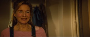 Movie still from “Bridget Jones's Baby” (2016), directed by Sharon Maguire – A woman in a pink shirt smiling for the camera; Close Up shot, Over the shoulder angle