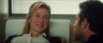 Movie still from “Bridget Jones's Baby” (2016), directed by Sharon Maguire – A woman sitting in a chair smiling at the camera; Close Up shot, Over the shoulder angle