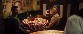 Movie still from “Bridget Jones's Baby” (2016), directed by Sharon Maguire – A woman sitting at a table with plates of food; Medium shot, Over the shoulder angle