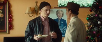 Movie still from “Bridget Jones's Baby” (2016), directed by Sharon Maguire – A man holding a plate of food talking to another man; Medium shot, Over the shoulder angle