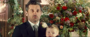 Movie still from “Bridget Jones's Baby” (2016), directed by Sharon Maguire – A man in a suit holding a child in a suit; Close Up shot, Over the shoulder angle