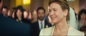 Movie still from “Bridget Jones's Baby” (2016), directed by Sharon Maguire – A person wearing a suit and smiling; Close Up shot, Over the shoulder angle
