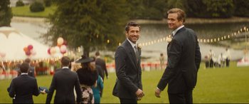 Movie still from “Bridget Jones's Baby” (2016), directed by Sharon Maguire – A couple of men standing next to each other on a field; Wide shot, Over the shoulder angle