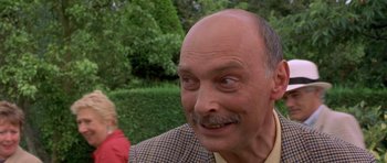 Movie still from “Bridget Jones's Diary” (2001), directed by Sharon Maguire – An older bald man with a mustache and a goatee looking at the camera; Close Up shot, Over the shoulder angle