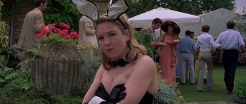 Movie still from “Bridget Jones's Diary” (2001), directed by Sharon Maguire – A woman wearing bunny ears and gloves in a garden setting; Medium shot, Over the shoulder angle