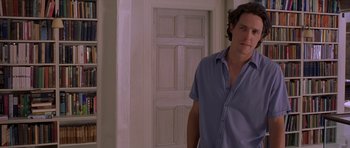 Movie still from “Bridget Jones's Diary” (2001), directed by Sharon Maguire – A man standing in front of a door wearing a blue shirt; Medium shot, Over the shoulder angle