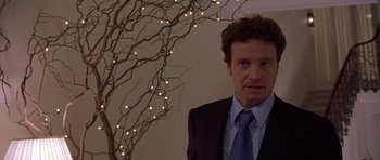 Movie still from “Bridget Jones's Diary” (2001), directed by Sharon Maguire – A man wearing a suit and tie standing next to a tree; Close Up shot, Over the shoulder angle