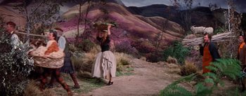 Movie still from “Brigadoon” (1954), directed by Vincente Minnelli – A painting of a woman carrying a basket on her head; Wide shot, High angle