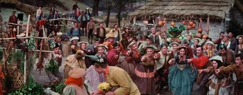 Movie still from “Brigadoon” (1954), directed by Vincente Minnelli – A group of people dressed in costumes in front of a crowd of onlookers; Wide shot, High angle