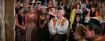 Movie still from “Brigadoon” (1954), directed by Vincente Minnelli – A group of people standing around each other wearing hats; Medium shot, High angle